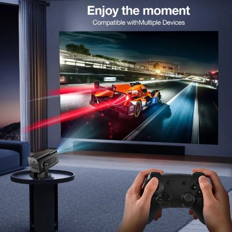 Projector displaying a racing game on a screen with hands holding a gaming controller.
