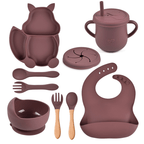 Children's silicone dining set with various pieces including a cup, bowl, spoon, and bib on a white background.