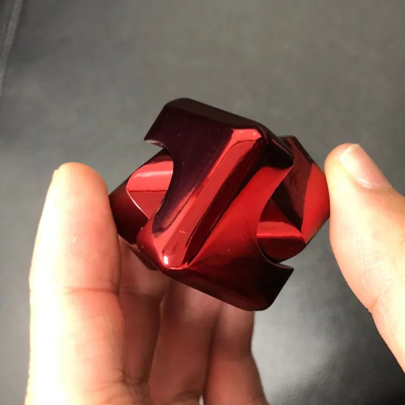 Red metal object held between fingers against a dark background