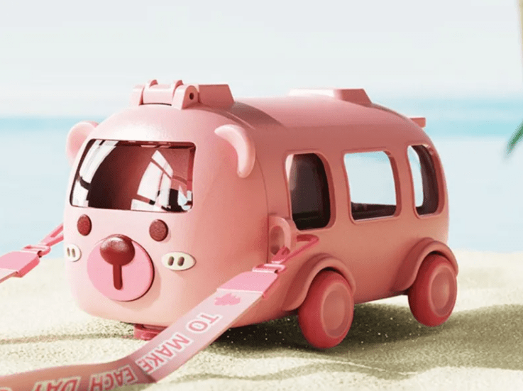 Pink toy bus with a sand shovel on a beach
