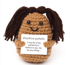 Crocheted potato with dreadlocks holding a sign on a white background