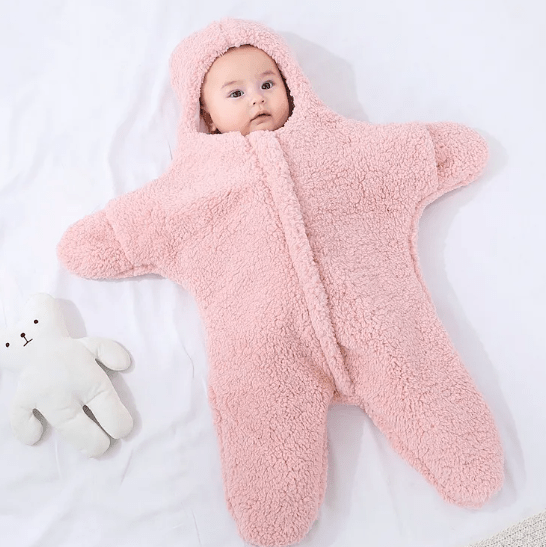 Baby in a pink star-shaped sleeping bag on a white background