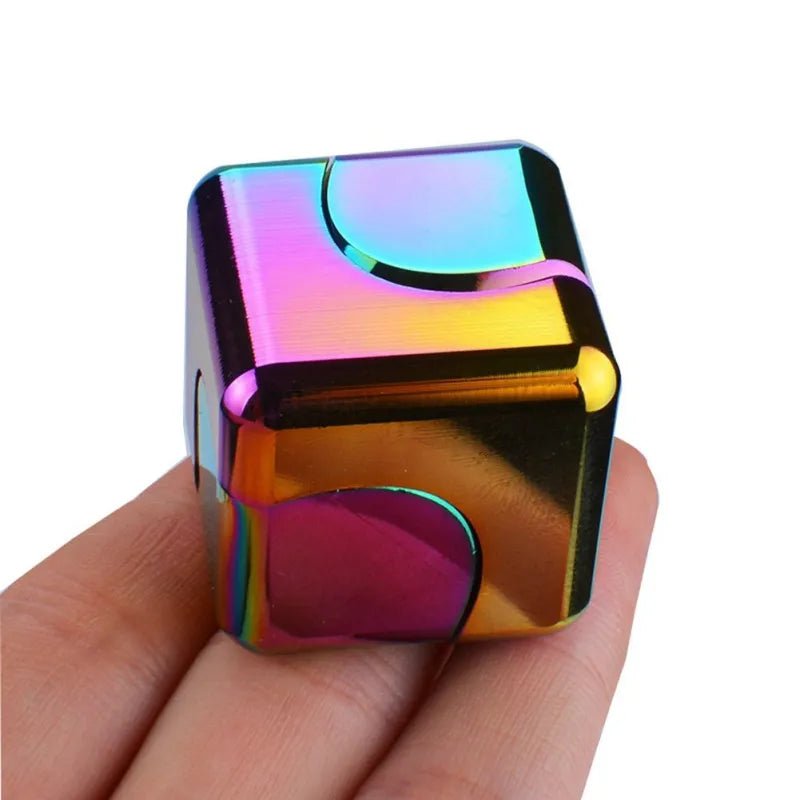 Multicolored metallic cube held in a hand against a white background