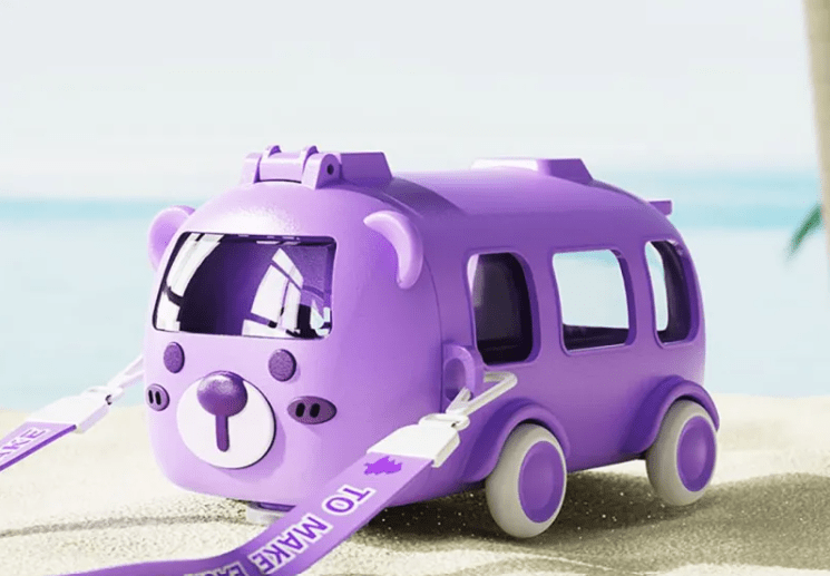 Purple toy bus with a bear face on a sandy beach