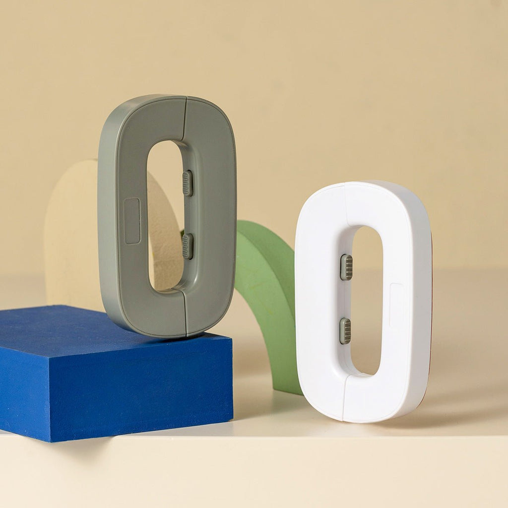 Two letter 'O' shaped objects, one gray and one white, on a beige background.