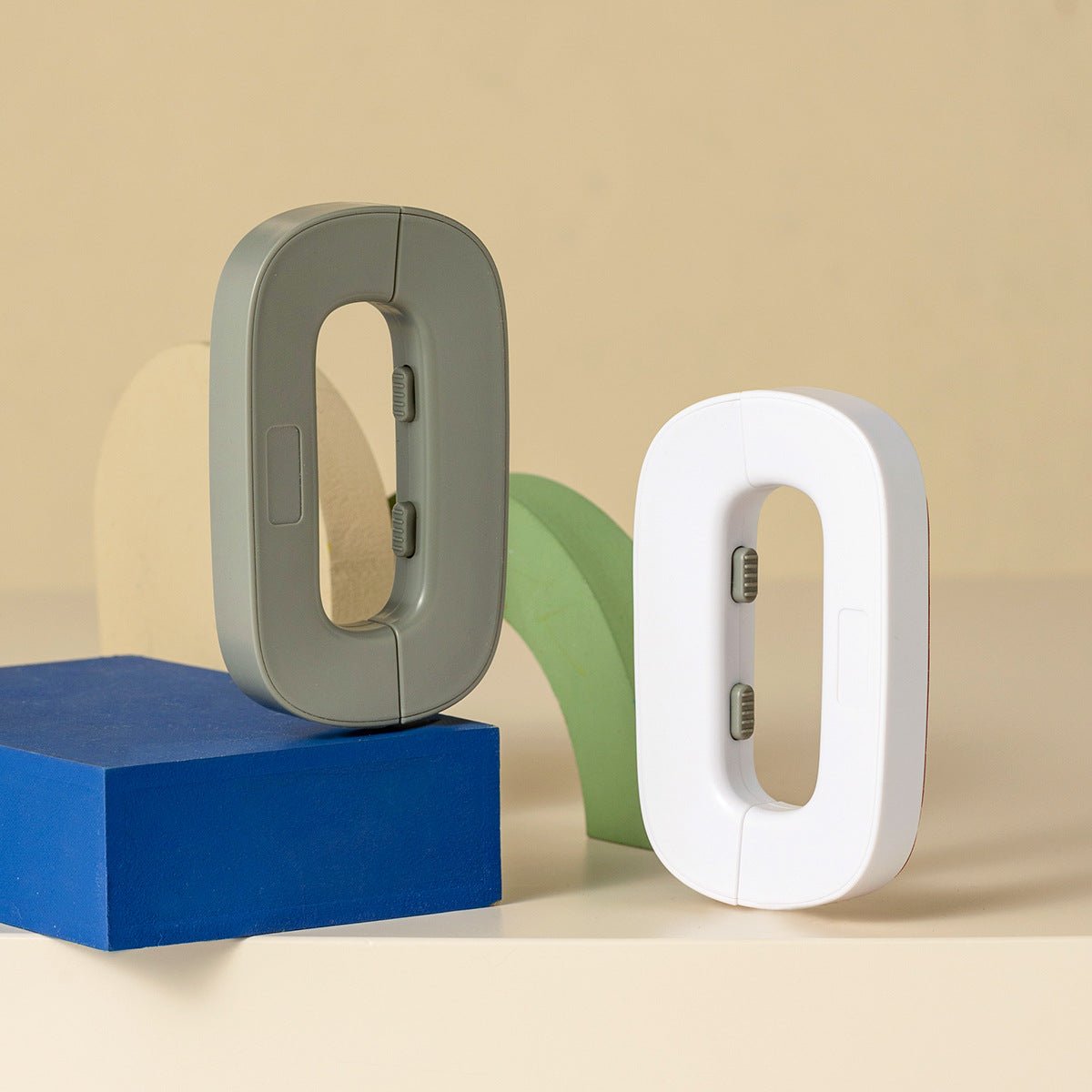Two letter 'O' shaped objects, one gray and one white, on a beige background.