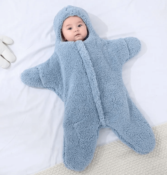 Baby in a blue fluffy snowsuit lying on a white blanket