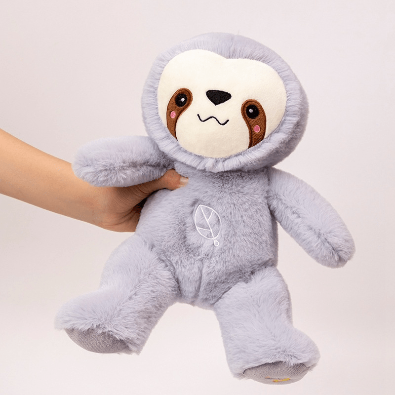 Plush toy sloth with a hand holding it against a light background