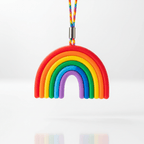 A colorful rainbow-shaped silicone accessory with a braided rainbow strap, suspended against a clean white background.